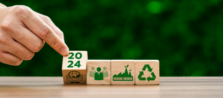 Eine Hand dreht einen Würfel um, auf welchem 2024 und 2024 steht. Daneben sind weitere Würfel, die Symbolbilder zum Thema Nachhaltigkeit enthalten.
