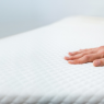 Eine Hand streicht über eine weiße Matratze